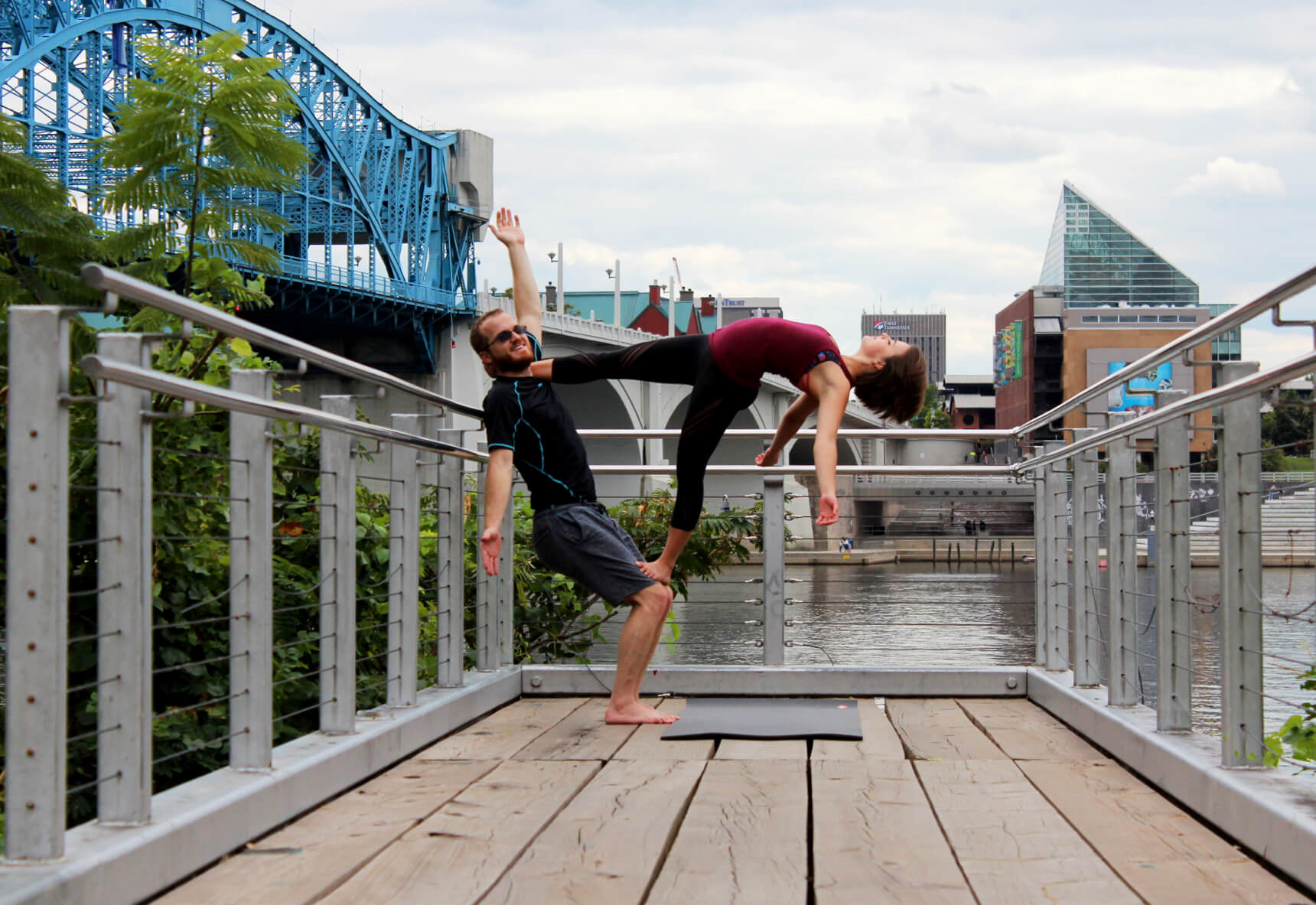 lydia and husband nick doing acro yoga by the walking bridge in chattanooga