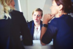 Woman in a blazer facing two other corporate women