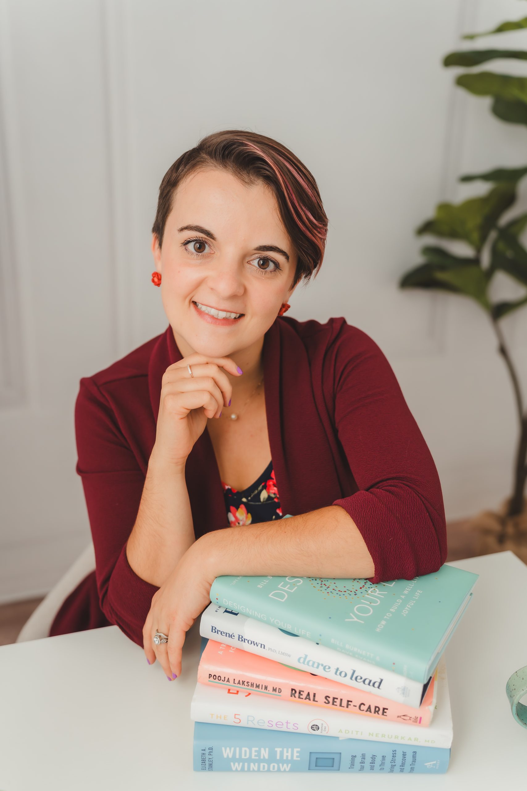 Lydia with Books Lydia Fogo Johnson, burnout and career coach, with a stack of leadership & wellbeing books